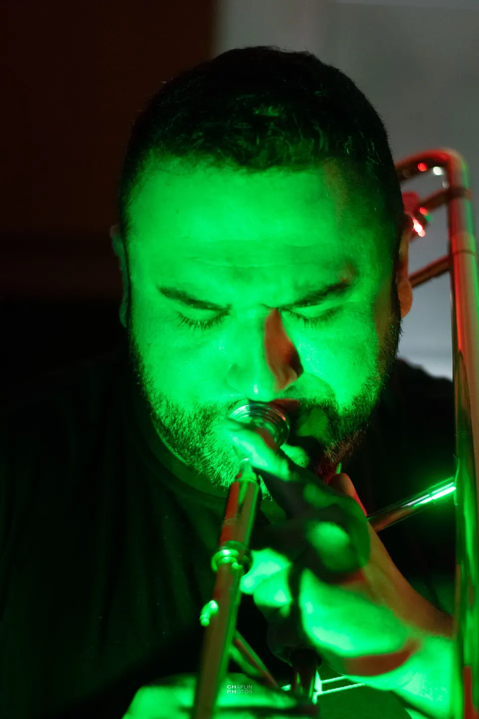 Trombonista toca sob luz verde.