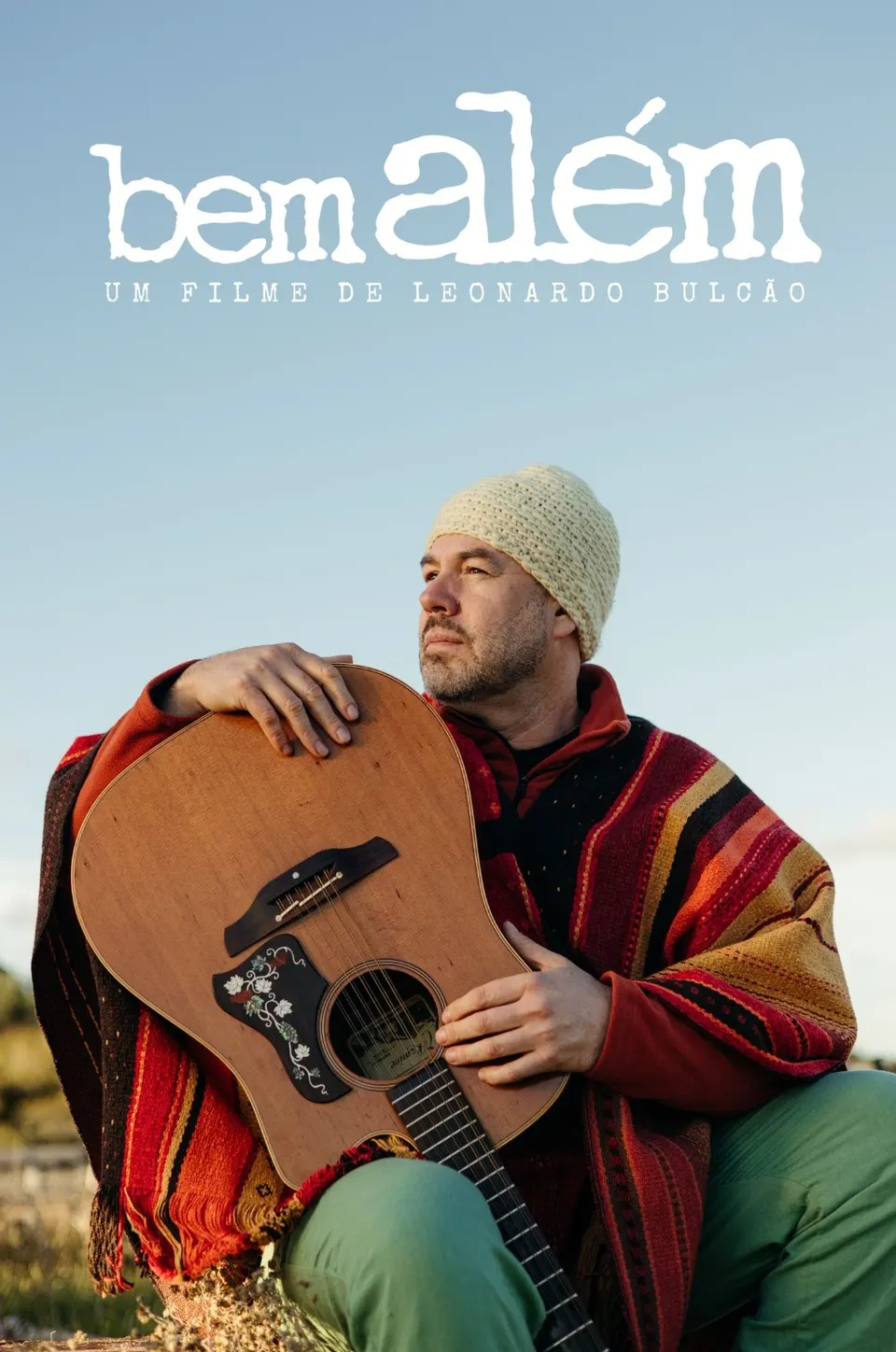 Cartaz do filme Bem Além, de Leonardo Bulcão: ele de poncho, abraçado a um violão, sob o título escrito no céu.