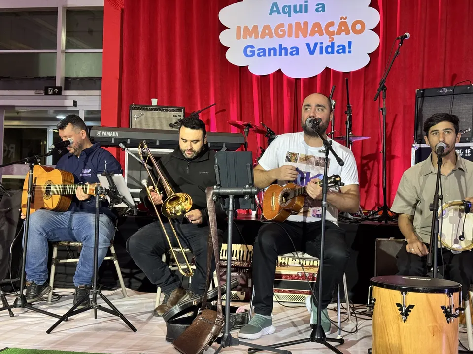 Professores e alunos da escola tocam violão, trombone e percussão no palco do Partage Shopping.
