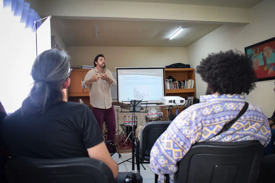 Palestra na sala Mentes MusiCaos, com o público sentado diante do telão.